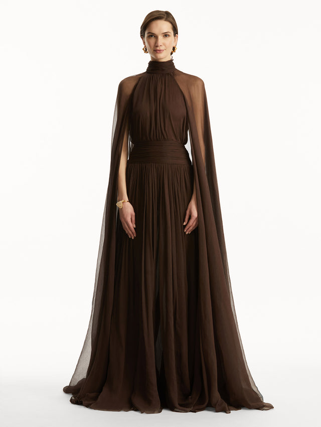 Brown chiffon gown with halter neck and long cascading sheer sleeves down the floor. Front view