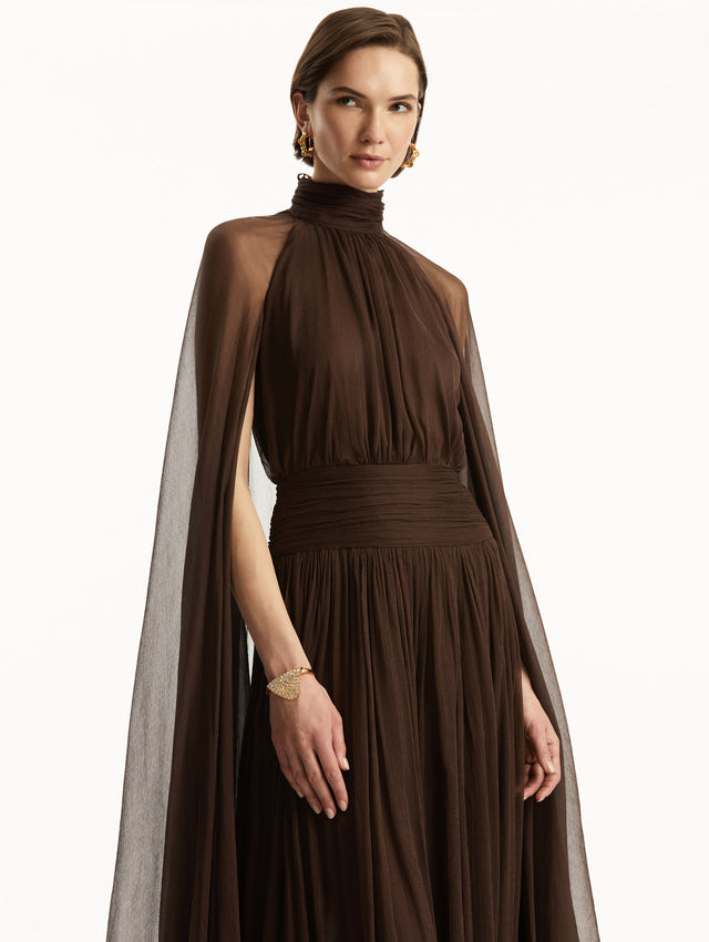 Brown chiffon gown with halter neck and long cascading sheer sleeves down the floor. Zoom view