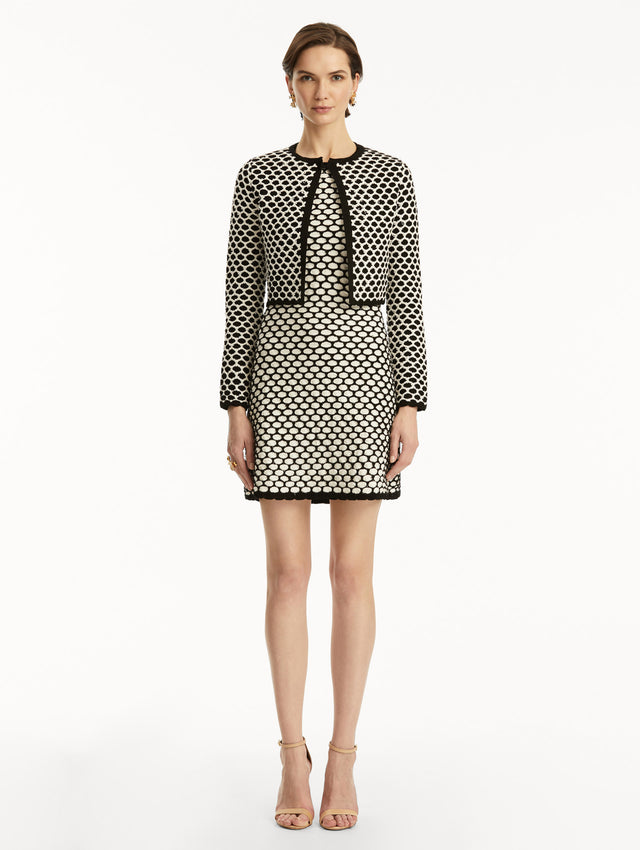 Model wearing black and white honeycomb print sequin knit jacket, paired with a matching dress. Front view