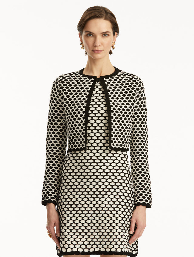 Model wearing black and white honeycomb print sequin knit jacket, paired with a matching dress. Front view
