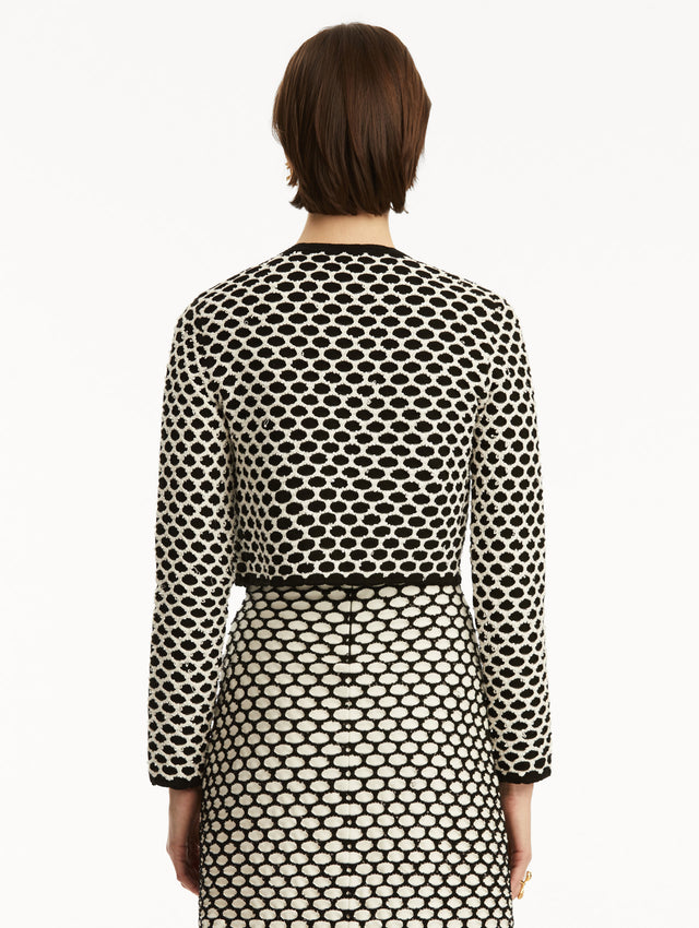 Model wearing black and white honeycomb print sequin knit jacket, paired with a matching dress. Back view