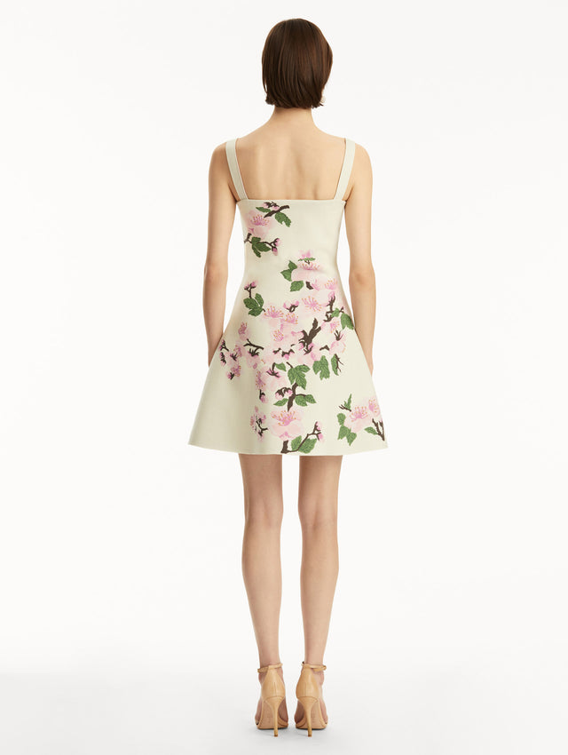 White knit mini jacquard sleeveless dress with pink cherry blossom print. Back view.