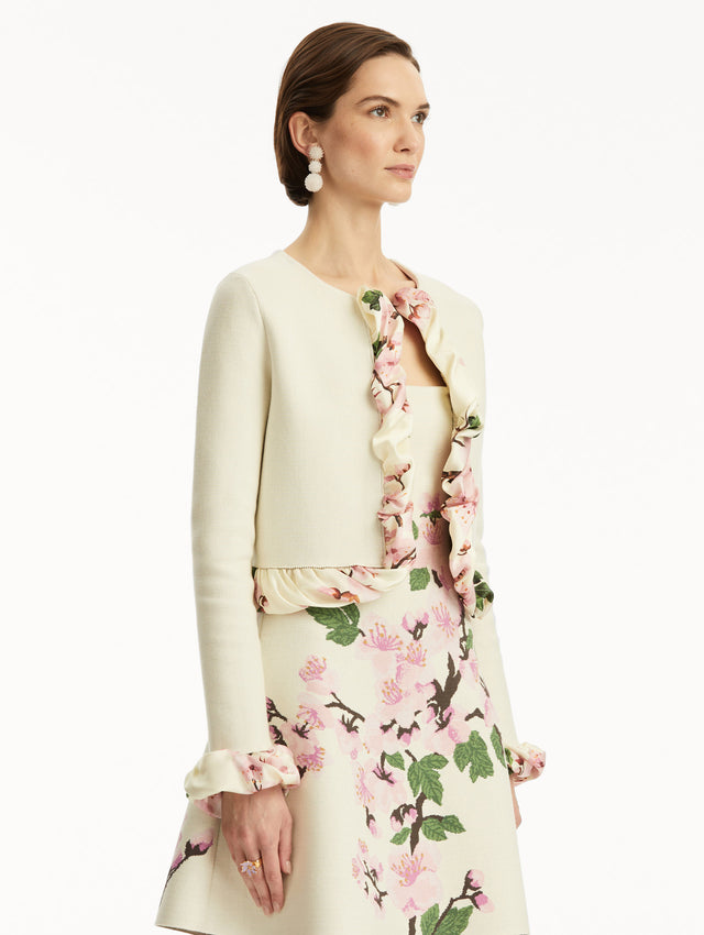 White cardigan with pink bubble twist trim printed with cherry blossoms, paired with cherry blossom tweed dress. Side view