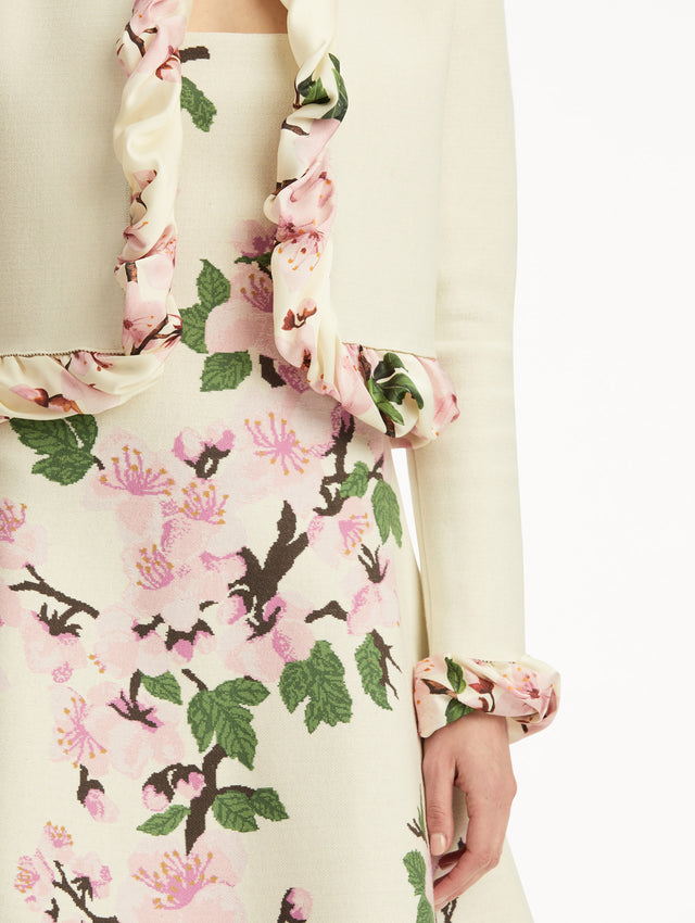 White cardigan with pink bubble twist trim printed with cherry blossoms, paired with cherry blossom dress. Zoom view