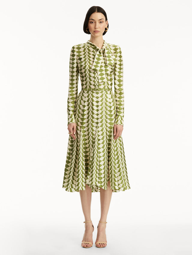 Long sleeve green and white geometric print silk midi dress with tie detail around the neck. Front view