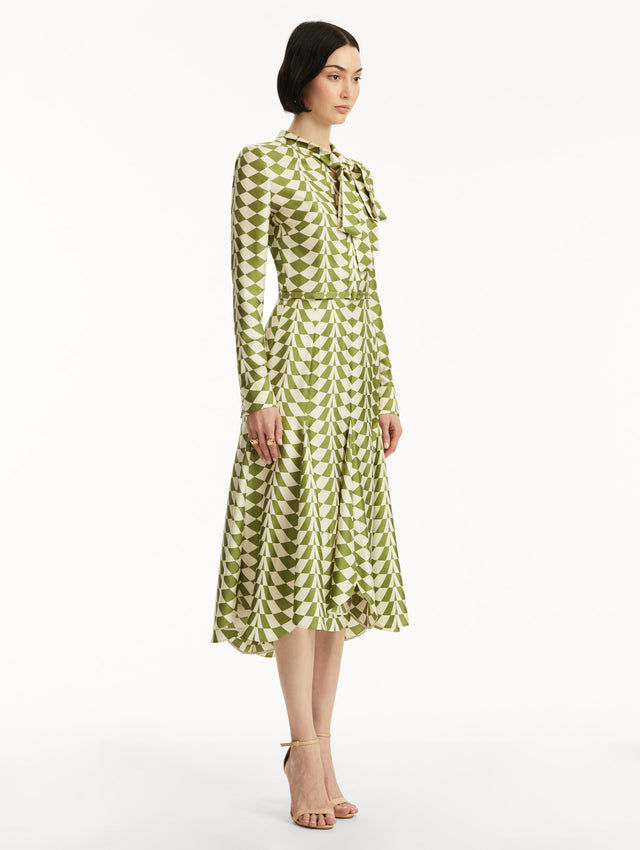 Long sleeve green and white geometric print silk midi dress with tie detail around the neck. Side view