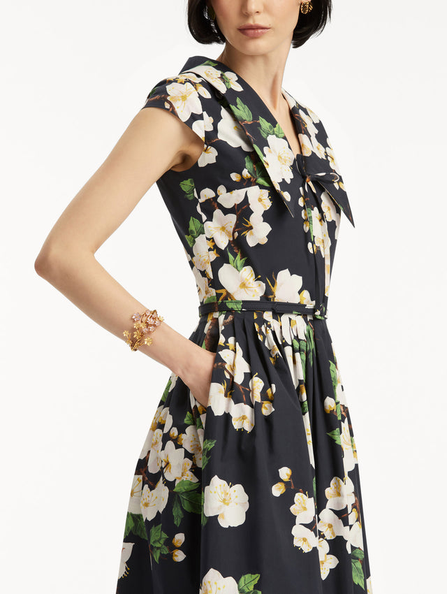 Model wears the Cherry Blossom Cotton Poplin Pleated Dress in a White and Navy floral print. Zoom View. 