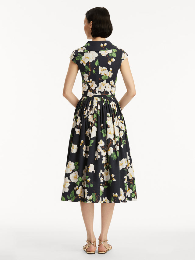 Model wears the Cherry Blossom Cotton Poplin Pleated Dress in a White and Navy floral print. Back View.