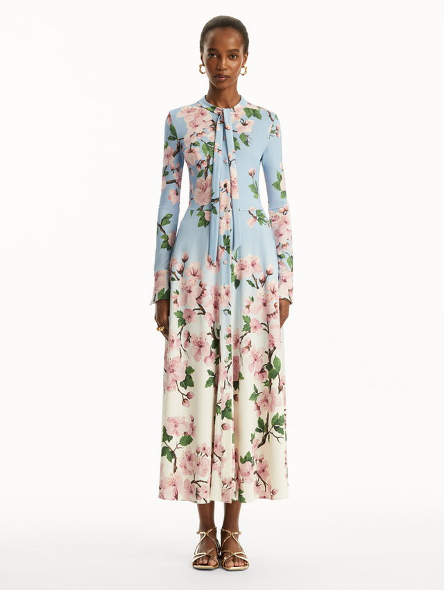 Ombre light blue to white long sleeve button-down long dress with tie detail on the neck and pink cherry blossom print. Front view