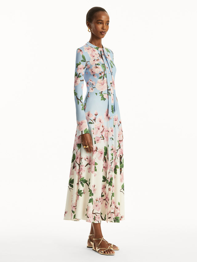 Ombre light blue to white long sleeve button-down long dress with tie detail on the neck and pink cherry blossom print. Side view