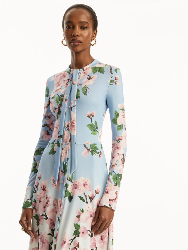 Ombre light blue to white long sleeve button-down long dress with tie detail on the neck and pink cherry blossom print. Zoom view