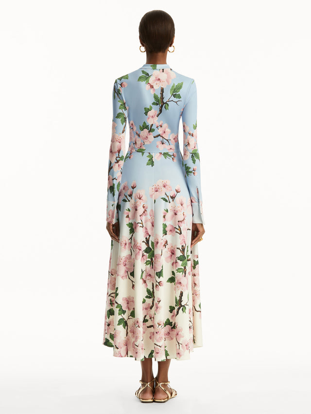 Ombre light blue to white long sleeve button-down long dress with tie detail on the neck and pink cherry blossom print. Back view