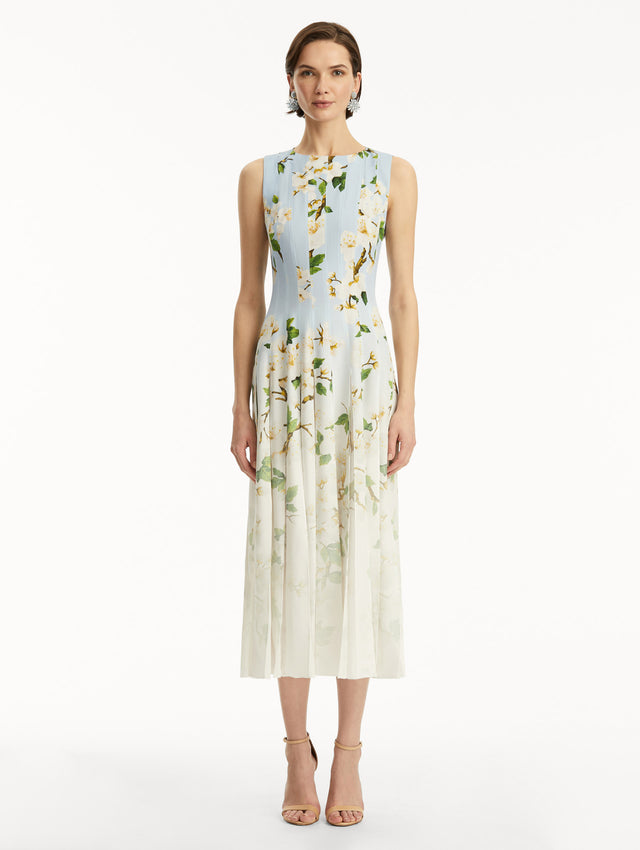 The model is wearing an ombre blue to white, sleeveless long dress with white cherry blossom print. Front view.