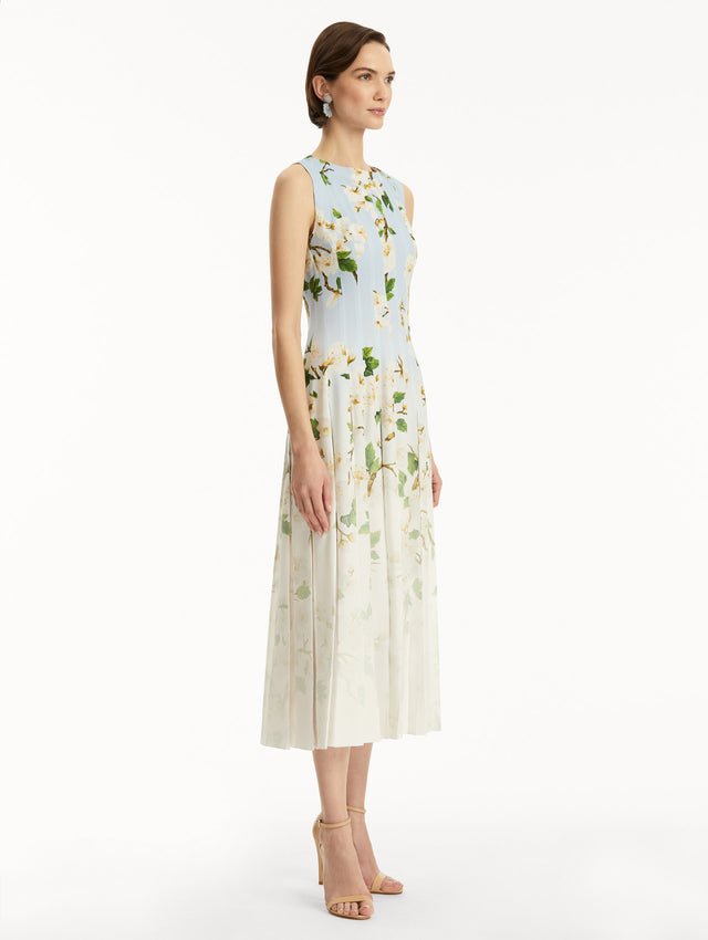 The model is wearing an ombre blue to white, sleeveless long dress with white cherry blossom print. Side view.