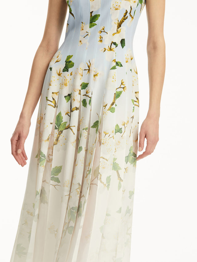 The model is wearing an ombre blue to white, sleeveless long dress with white cherry blossom print. Zoom view.