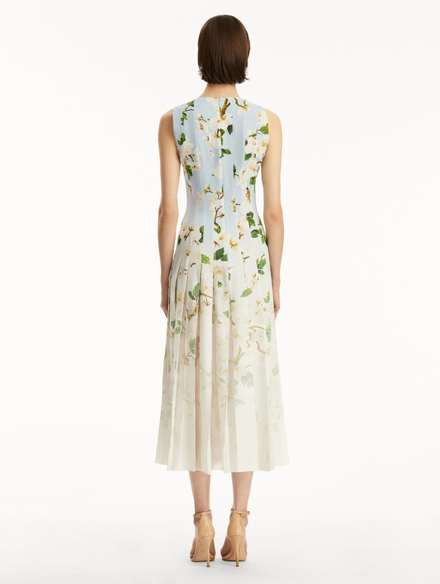 The model is wearing an ombre blue to white, sleeveless long dress with white cherry blossom print. Back view.