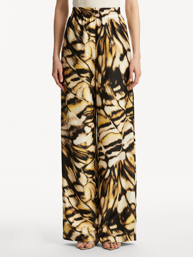 Abstract butterfly print in tones of yellow, brown/black, and white silk pants. Front view