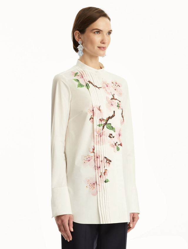 The model is wearing a white button-down blouse with pink cherry blossoms printed in the center. It is paired with Navy pants. Side view.