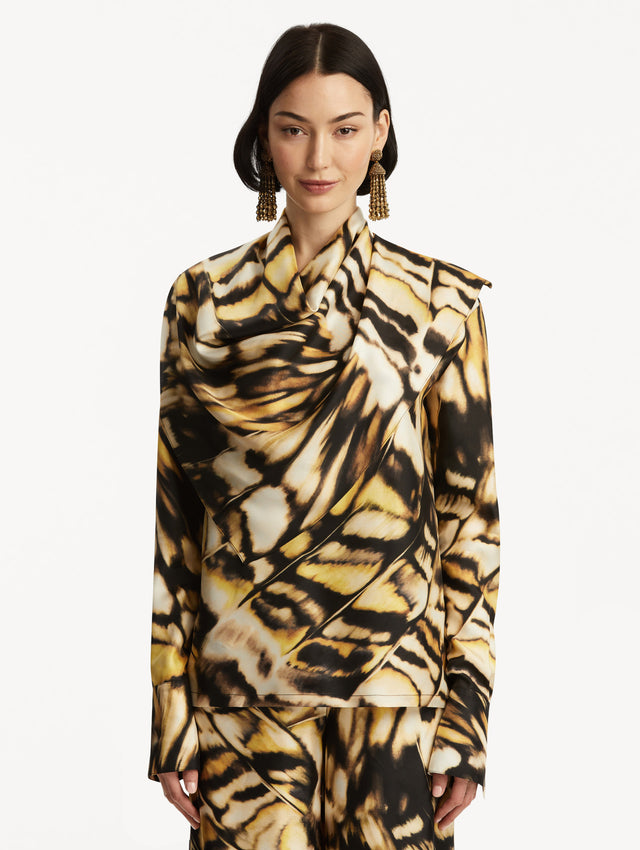 The model is wearing an abstract butterfly printed silk blouse, with draping around the neck, paired with matching pants. Front View. 