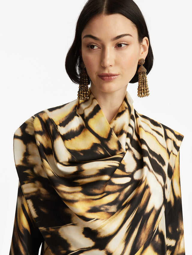 The model is wearing an abstract butterfly printed silk blouse, with draping around the neck, paired with matching pants. Zoom View. 