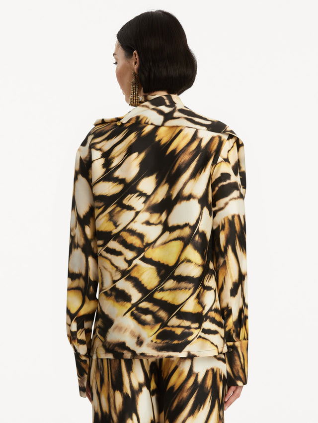 The model is wearing an abstract butterfly printed silk blouse, with draping around the neck, paired with matching pants. Back View. 