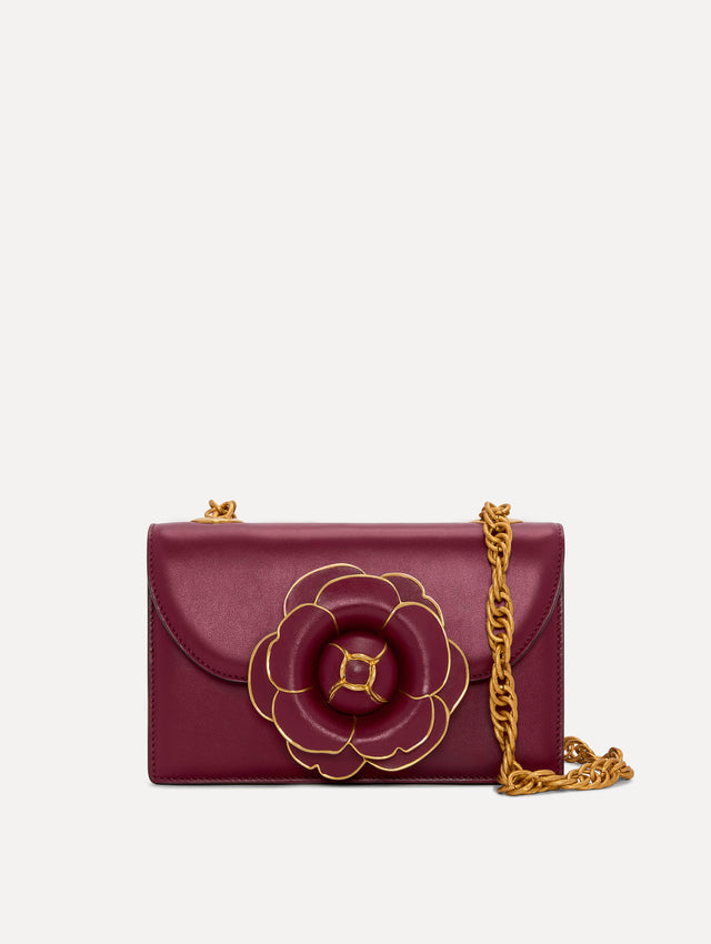 TRO Bag in red with flower applique at the clasp and gold detailing in the border of every petal. The bag also has a detachable gold shoulder strap. Front View