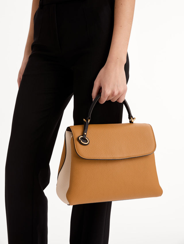 The Poppy Handbag in Honey with Black Top Handle and removeable shoulder strap. Adorned with Oscar de la Renta's signature O at the ornamental bag tag. Side View.