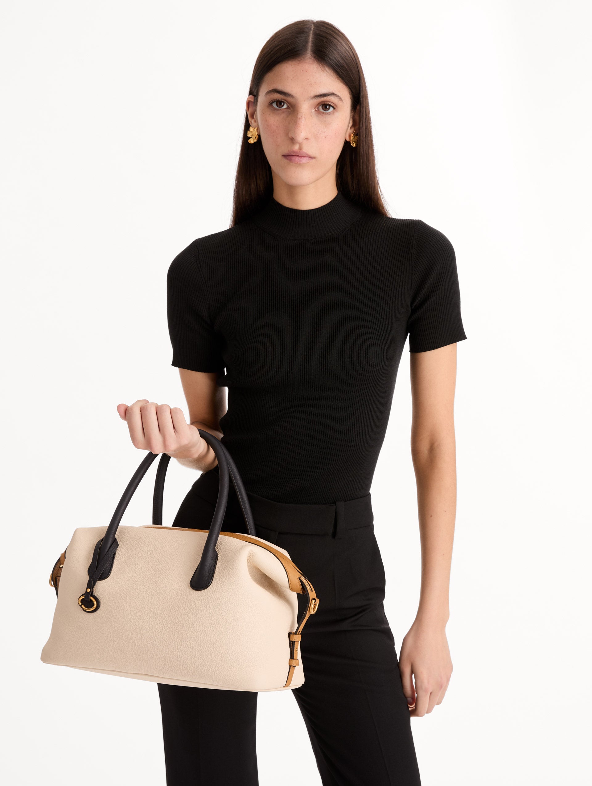The Dahlia Handbag in Ivory with Black Top Handle and Honey sides. Adorned with Oscar de la Renta's signature logo in the bottom center of the back of the bag. Front View.
