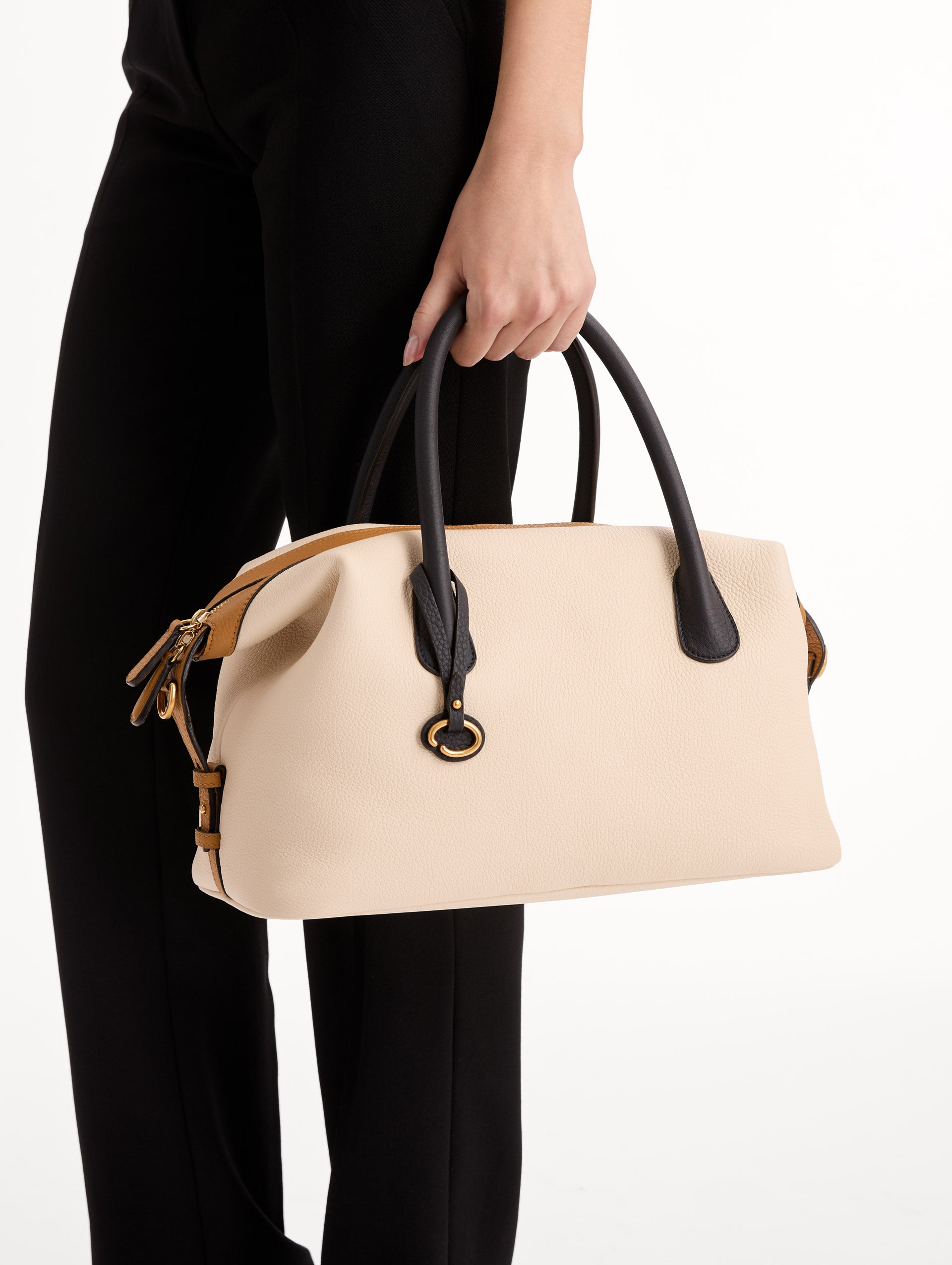 The Dahlia Handbag in Ivory with Black Top Handle and Honey sides. Adorned with Oscar de la Renta's signature logo in the bottom center of the back of the bag. Side View.