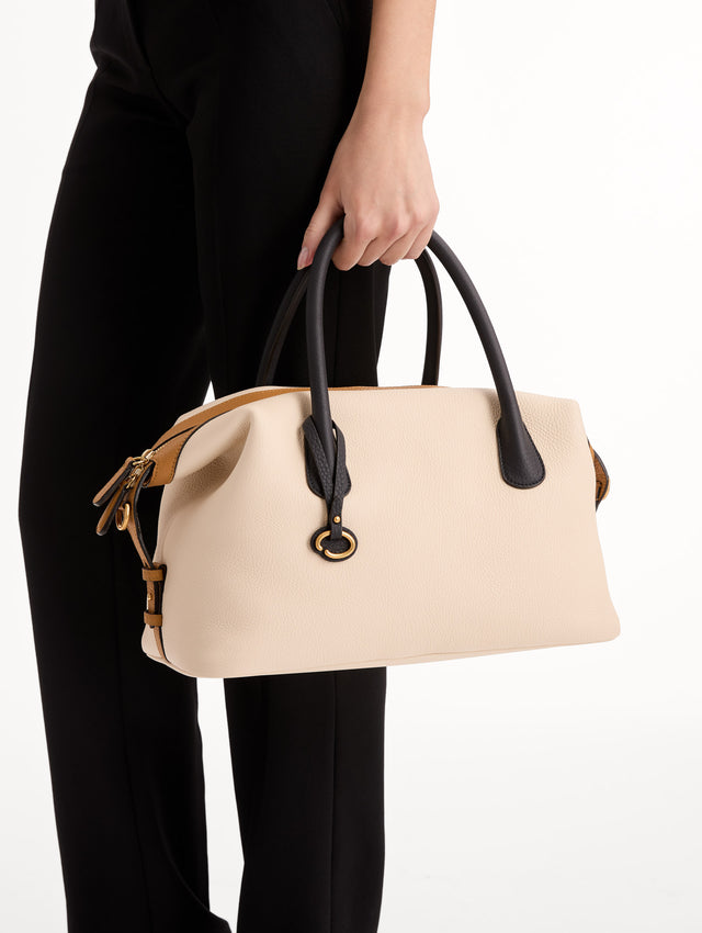 The Dahlia Handbag in Ivory with Black Top Handle and Honey sides. Adorned with Oscar de la Renta's signature logo in the bottom center of the back of the bag. Side View.