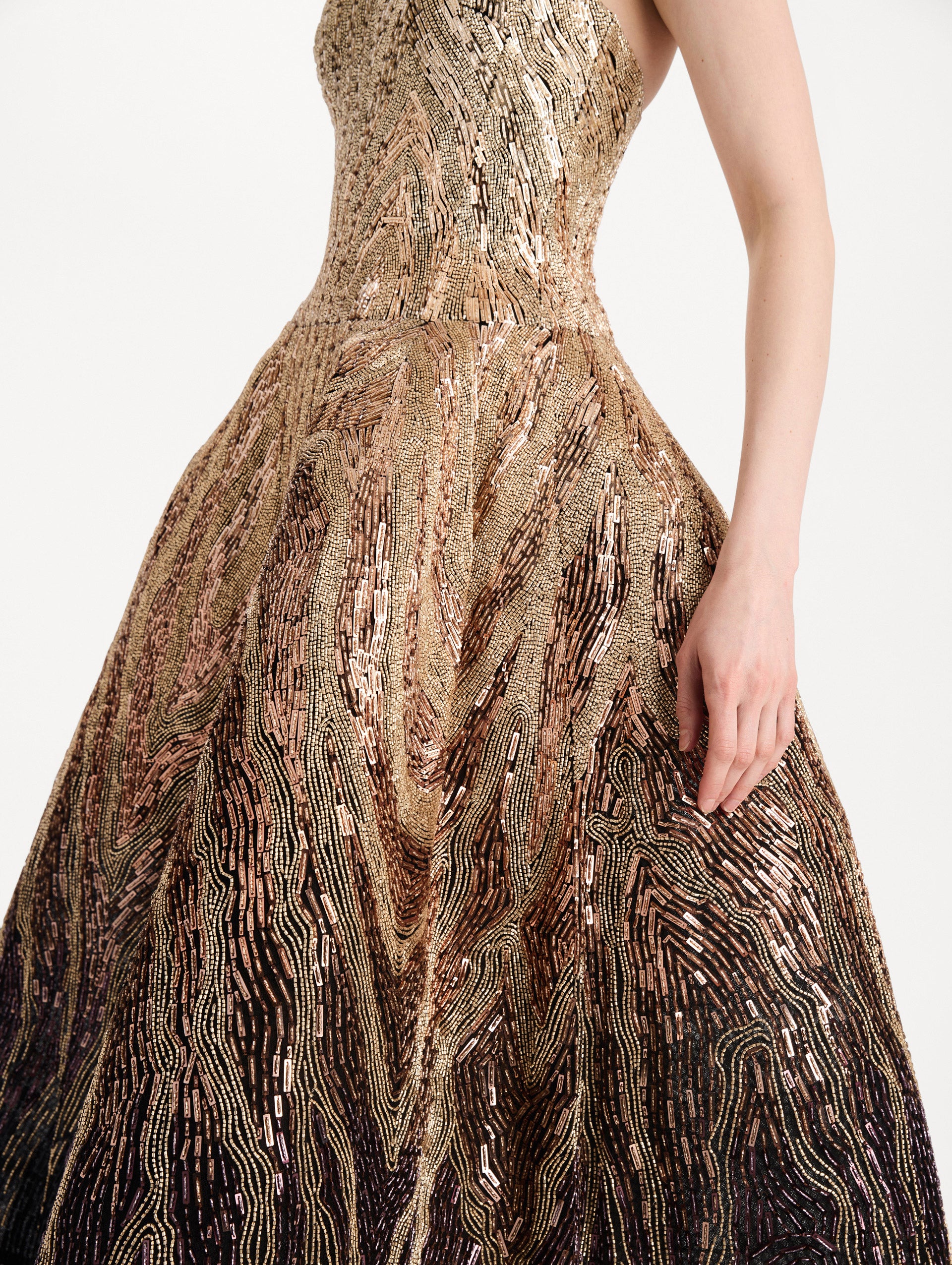 The model is wearing the beaded sequin moiré ombré tea length gown with a strapless silhouette and transitioning gold multi tones. Zoom view.