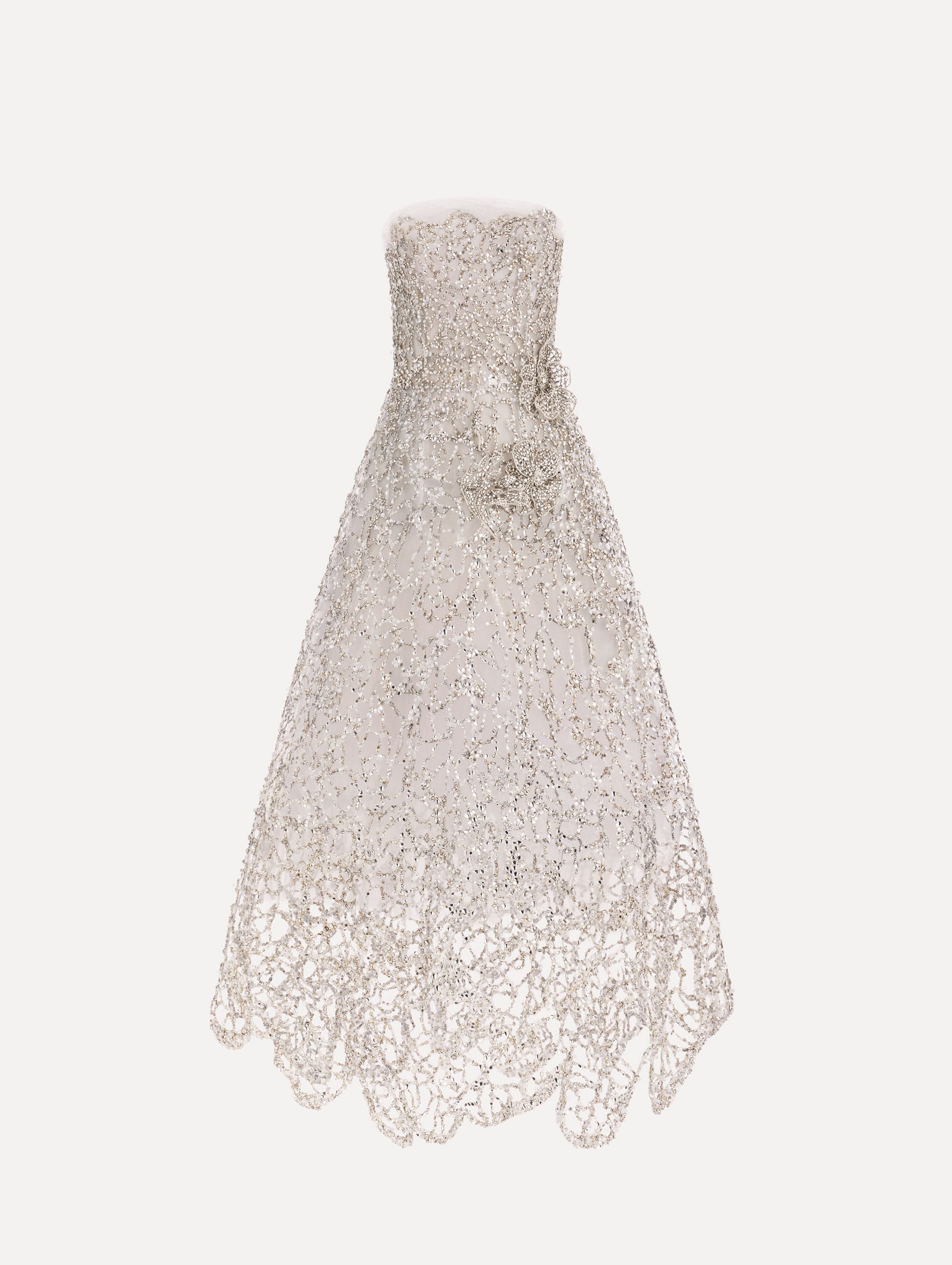 The model is wearing the crystal leaves embroidered gown with a strapless silhouette and crystal leaf detailing in the color silver.