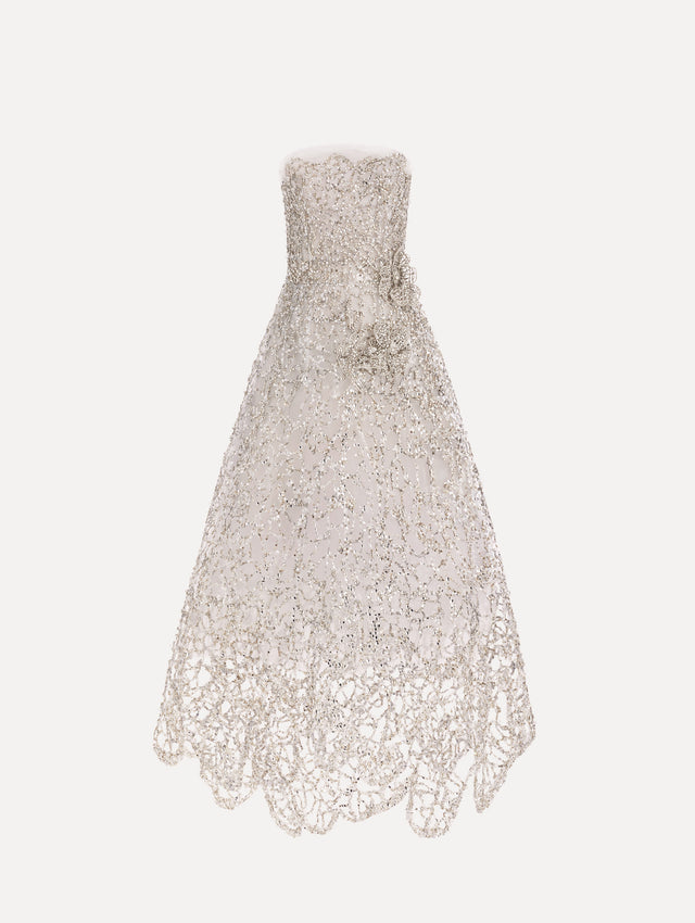 The model is wearing the crystal leaves embroidered gown with a strapless silhouette and crystal leaf detailing in the color silver.