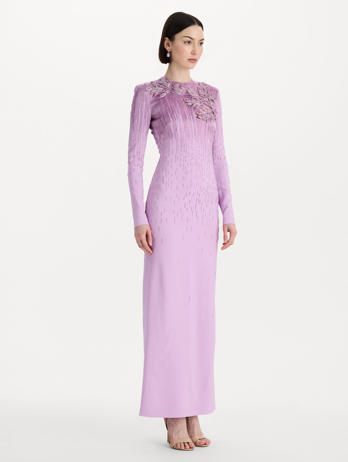 The model is wearing the intarsia leaves cutout embroidered gown with long sleeves in the color verbena. Side view. 