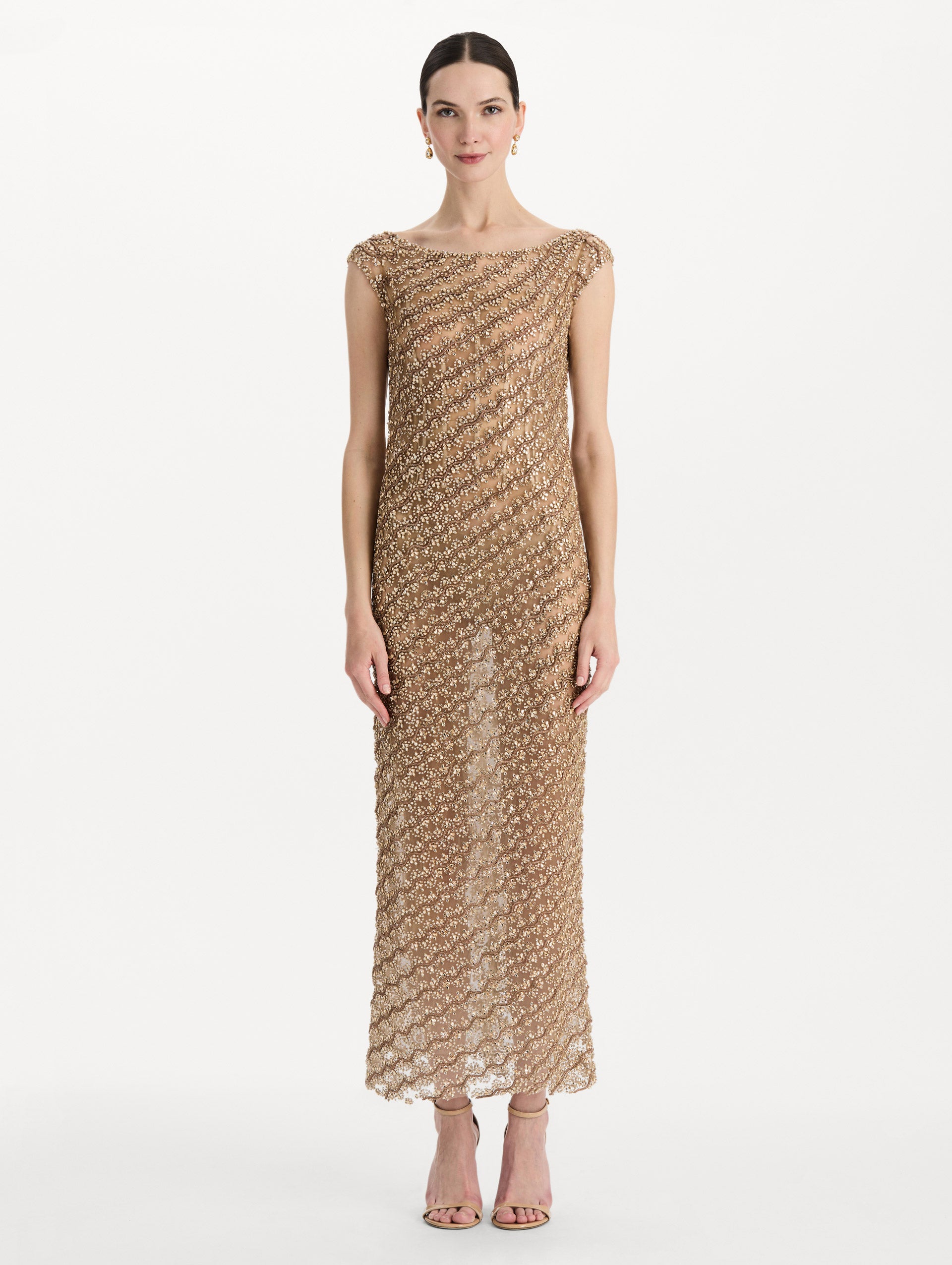 The model is wearing the beaded wave embroidered sleeveless cocktail dress in the color amber. Front view. 