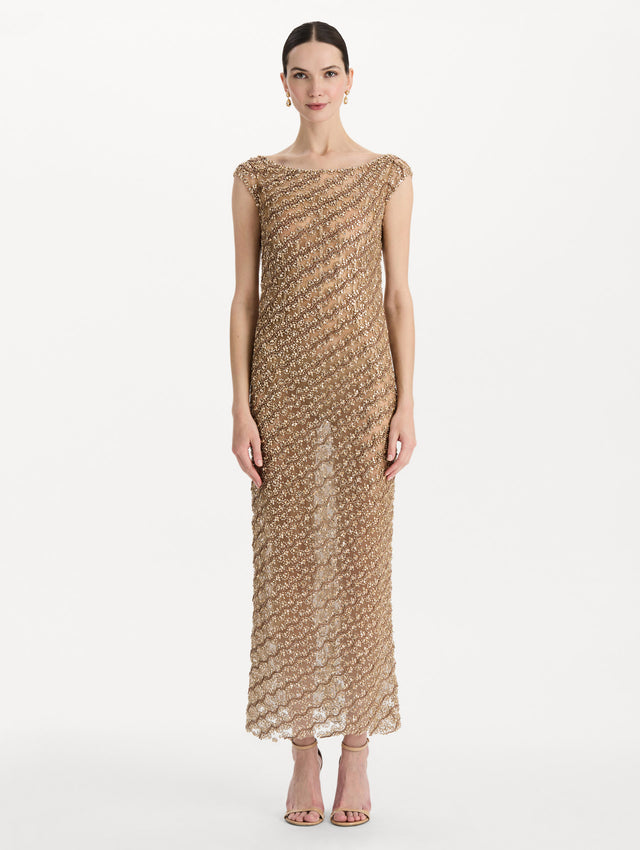 The model is wearing the beaded wave embroidered sleeveless cocktail dress in the color amber. Front view. 