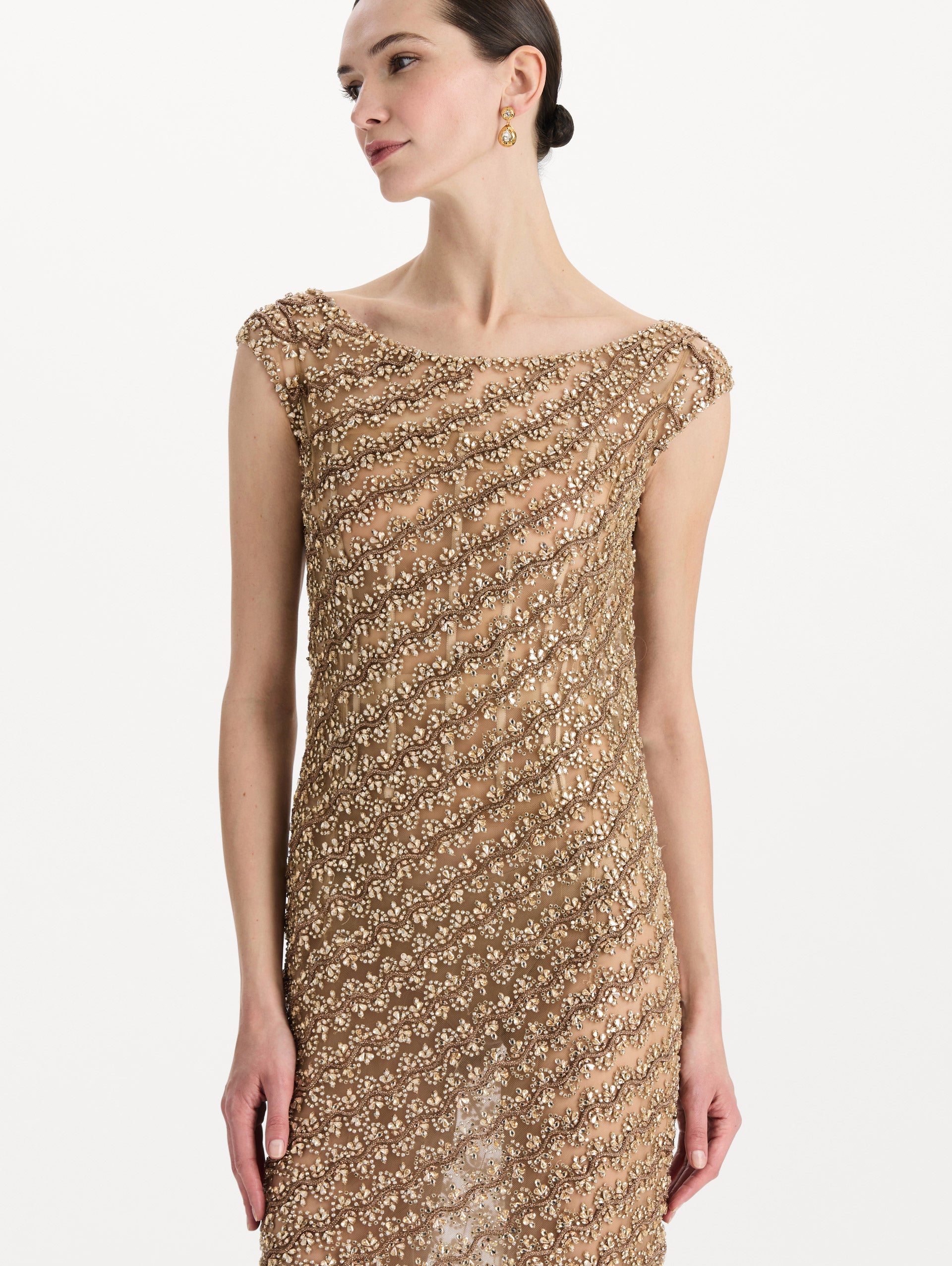 The model is wearing the beaded wave embroidered sleeveless cocktail dress in the color amber. Zoom view. 