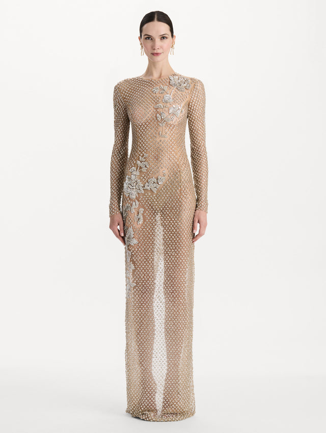 The model is wearing the crystal grid floral embroidered gown with long sleeves in the color silver. Front view.