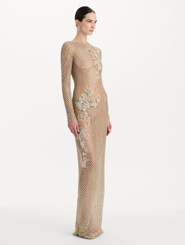 The model is wearing the crystal grid floral embroidered gown with long sleeves in the color silver. Side view.