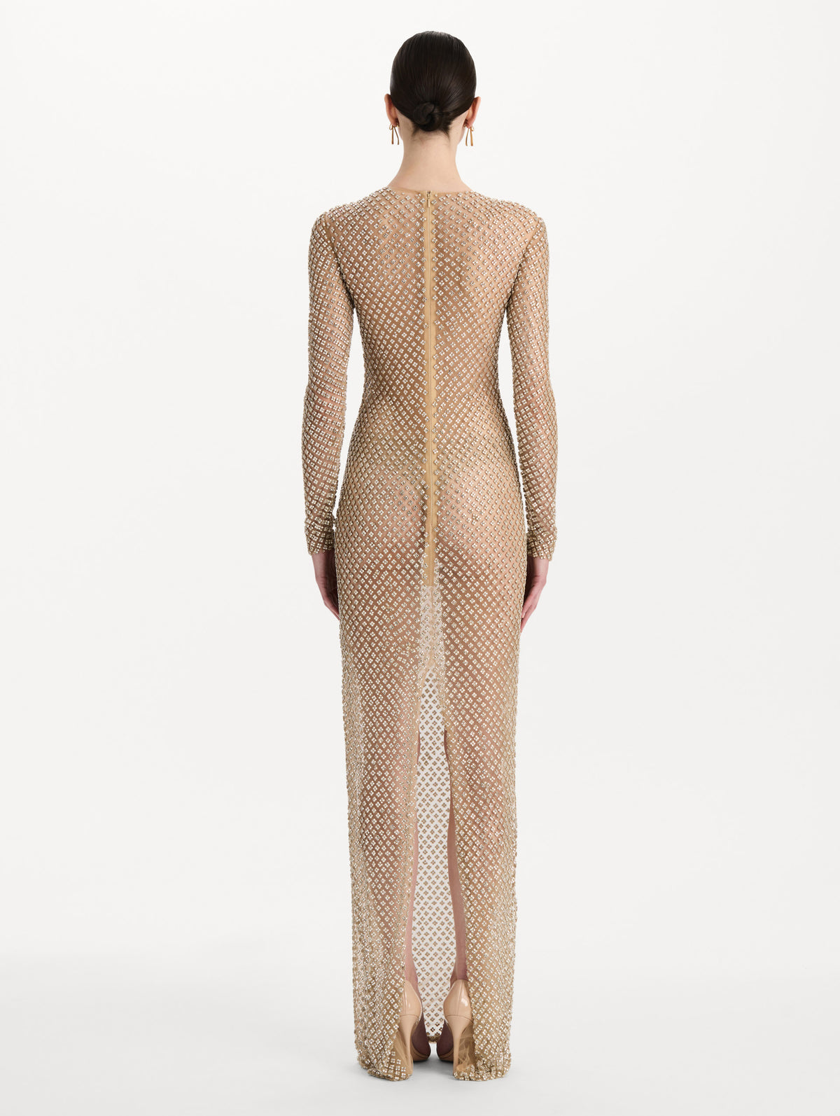 The model is wearing the crystal grid floral embroidered gown with long sleeves in the color silver. Back view.