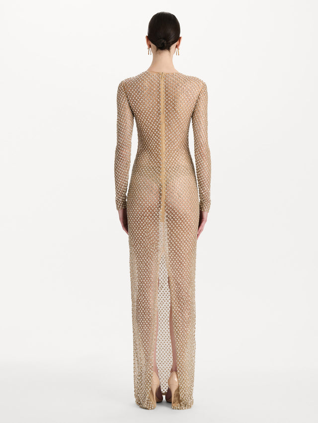The model is wearing the crystal grid floral embroidered gown with long sleeves in the color silver. Back view.