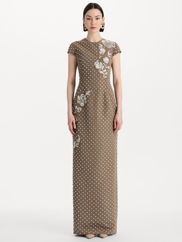The model is wearing the crystal grid floral embroidered gown with short sleeves in the color stone. Front view.