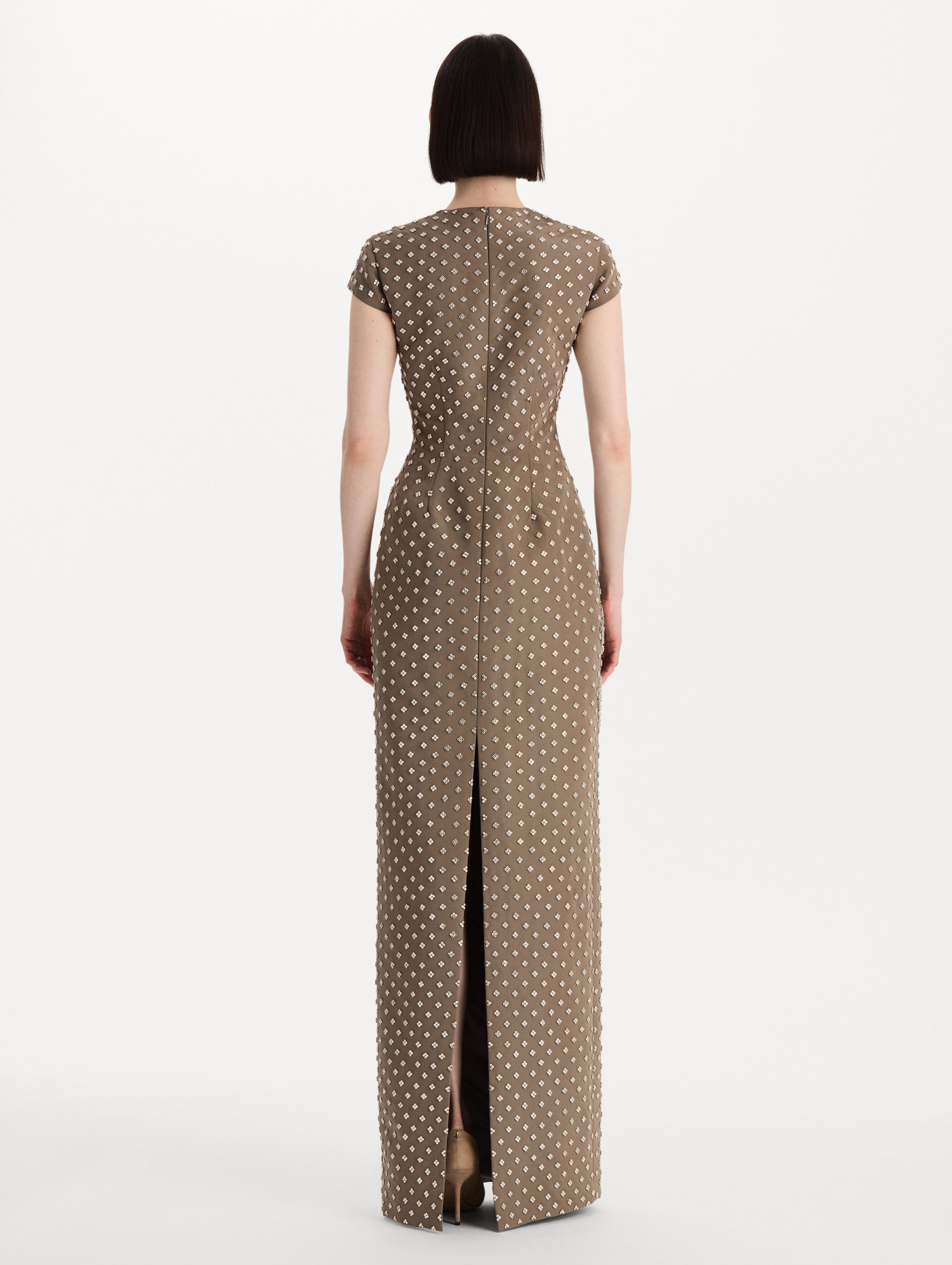 The model is wearing the crystal grid floral embroidered gown with short sleeves in the color stone. Back view.