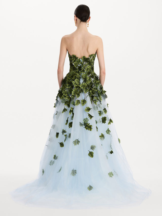 The model is wearing the maple leaf appliqué gown with a strapless silhouette in the color sky blue. Back view.