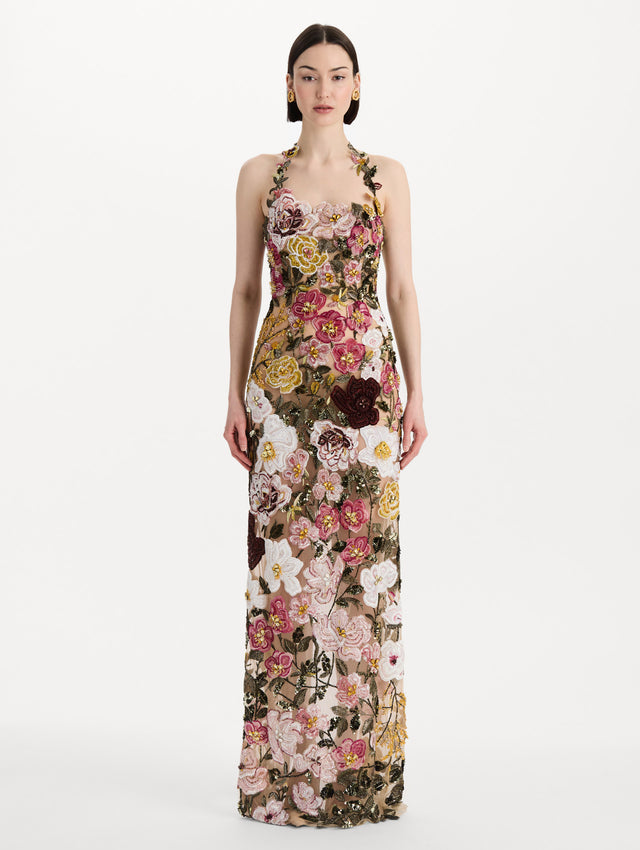 The model is wearing the beaded mixed botanical embroidered gown in multi-color with a halter neckline and floral detailing. Front view.