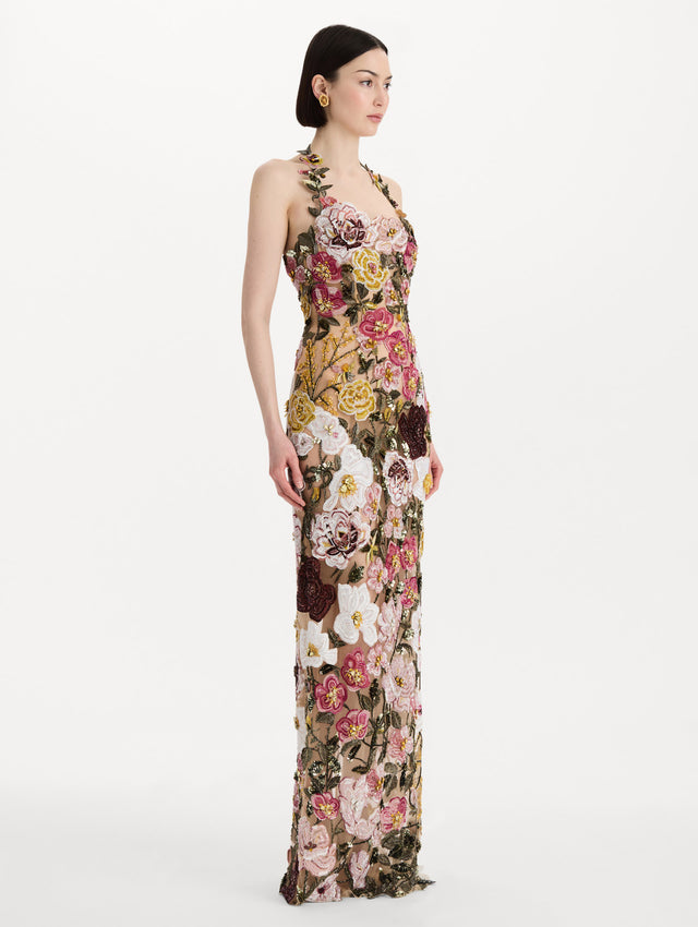 The model is wearing the beaded mixed botanical embroidered gown in multi-color with a halter neckline and floral detailing. Side view.