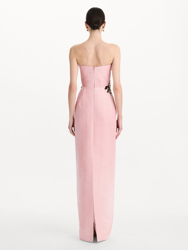 The model is wearing the beaded mixed botanical embroidered column gown with floral detailing and a strapless silhouette in the color blush. Back view.