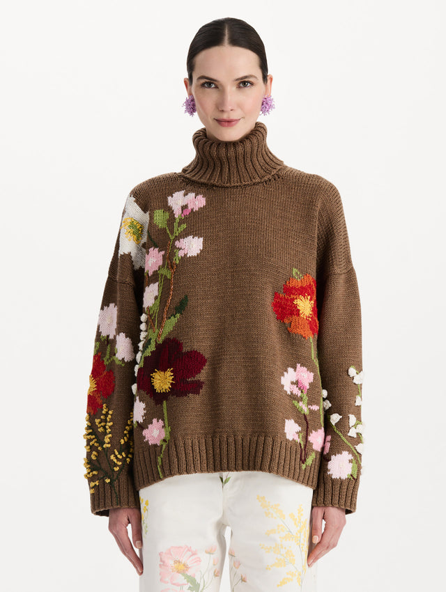 The model is wearing the mixed botanical embroidered oversized pullover with a floral intarsia pattern in the color brown. Front view.
