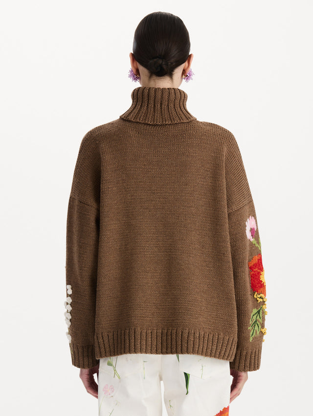 The model is wearing the mixed botanical embroidered oversized pullover with a floral intarsia pattern in the color brown. Back view. 