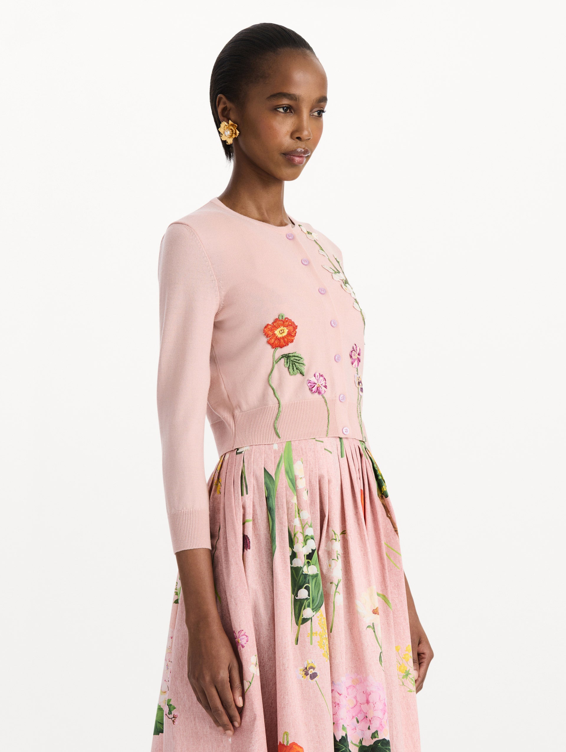 The model is wearing the mixed botanical threadwork cardigan in the color blush with floral detailing. Side view.